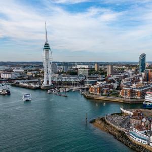 Aerial view of Gunwharf Quays and the iconic Spinnaker Tower in Portsmouth, showcasing the vibrant waterfront, marina and Solent coastline.